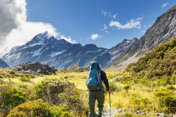 person hiking in a mountain surrounded by green fields