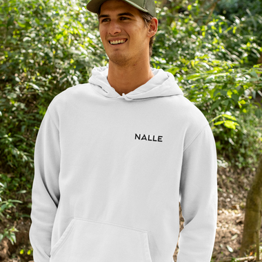 Man wearing a gray hoodie with the Nalle logo on hiking in a forest.