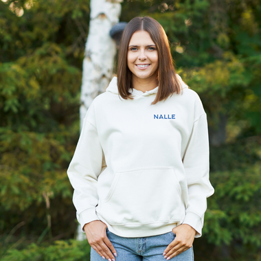 Woman wearing a gray hoodie with the Nalle logo on hiking in a forest.