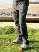 Man wearing gray hiking pants with Nalle on the thigh hiking on a beach.