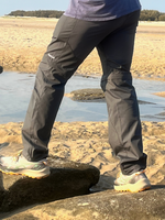 Man wearing gray hiking pants with Nalle on the thigh hiking on a beach.