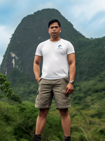 Man wearing a white tee with the Nalle logo standing in front of a mountain, hiking