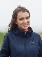 Girl with damp hair wearing a navy blue rain jacket with Nalle logo in the outdoors.