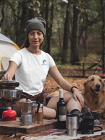 Woman wearing a white t-shirt with the Nalle logo on camping in the forest with a Golden Retriever by her side. 