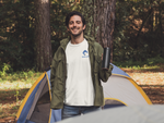 Man wearing a white t-shirt with the Nalle logo on camping in the forest